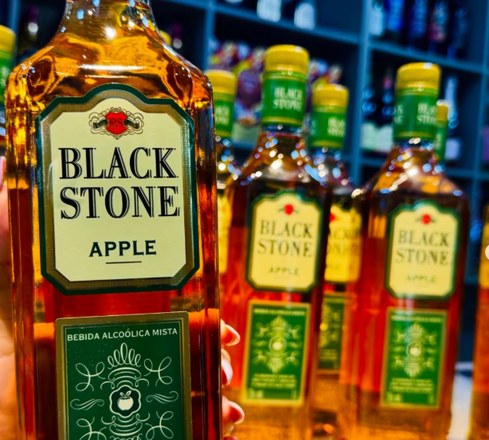 Garrafas de whisky Black Stone Apple alinhadas na prateleira da loja